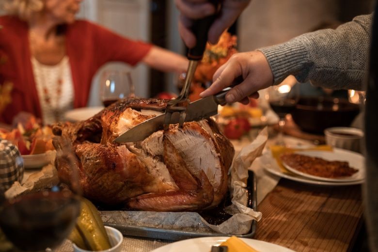 Family carving turkey at dinner table